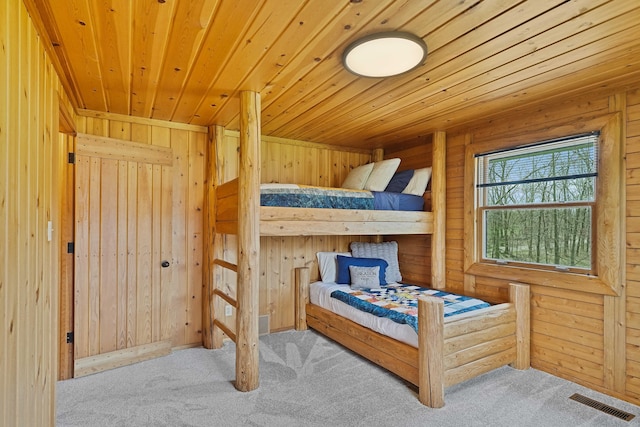 bedroom featuring wooden ceiling, carpet flooring, wood walls, and visible vents