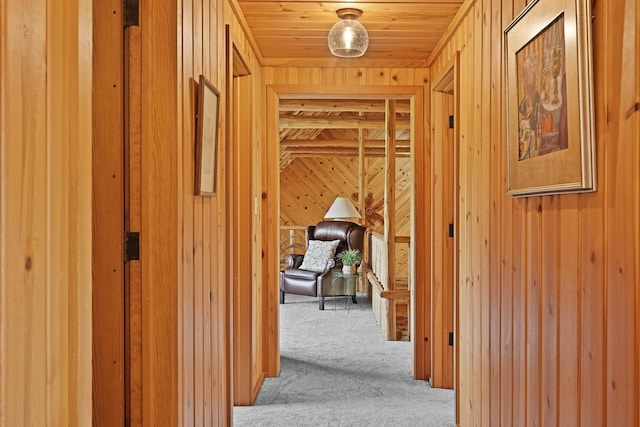 hall featuring wooden walls, wood ceiling, and carpet