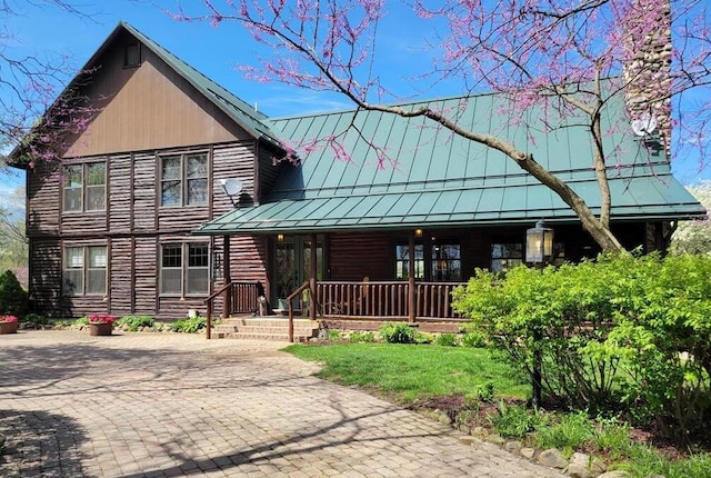 log cabin featuring a porch, a standing seam roof, and metal roof