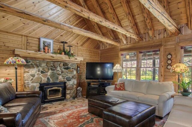 living area with wood ceiling, a stone fireplace, wood walls, high vaulted ceiling, and beamed ceiling