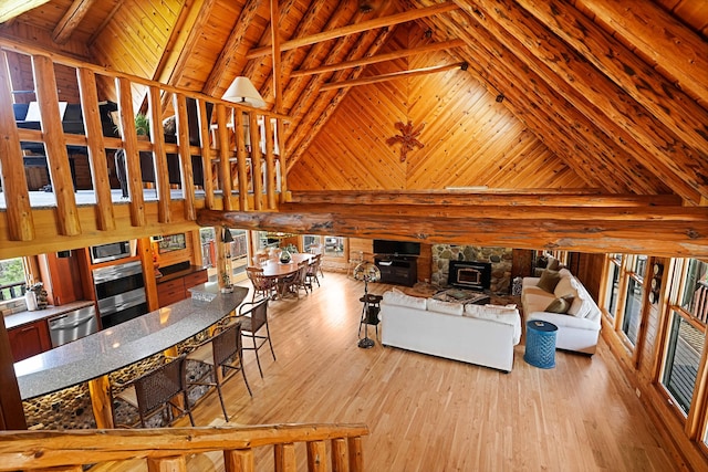 living room with beam ceiling, wood finished floors, wooden walls, high vaulted ceiling, and wood ceiling