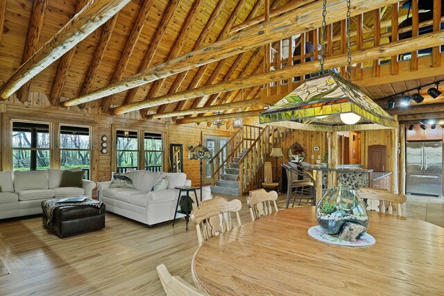 dining space featuring wooden walls, wood ceiling, stairs, and beam ceiling