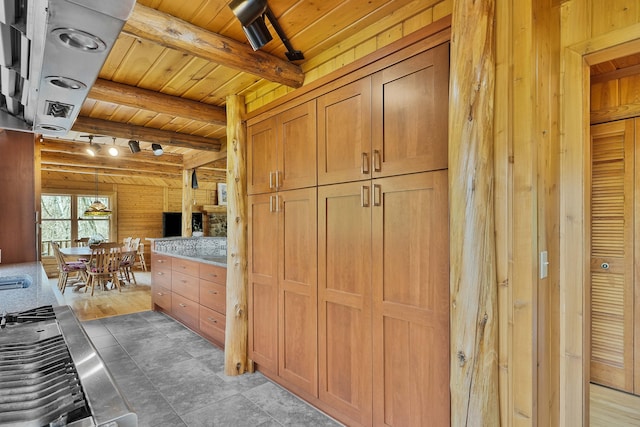 kitchen featuring light countertops, beam ceiling, wooden walls, and wooden ceiling