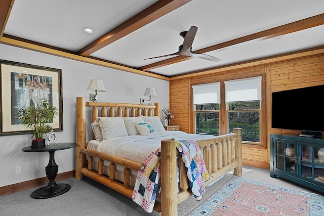 bedroom with carpet flooring, a ceiling fan, wood walls, and beam ceiling