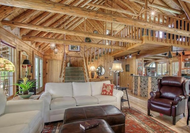 living room with wooden walls, stairs, a wealth of natural light, and wood finished floors
