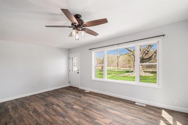 unfurnished room featuring dark wood-style flooring, baseboards, visible vents, and a ceiling fan
