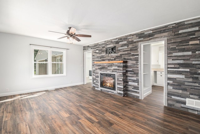 unfurnished living room with ceiling fan, a large fireplace, baseboards, wood finished floors, and visible vents
