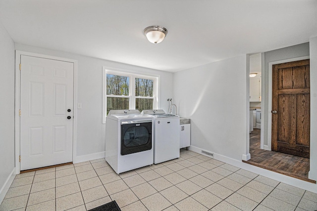 clothes washing area featuring laundry area, visible vents, light tile patterned floors, baseboards, and separate washer and dryer