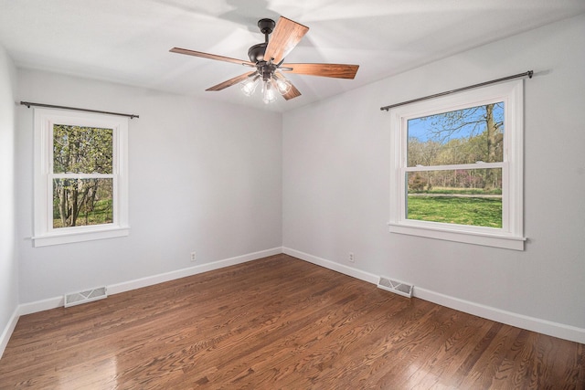 empty room with visible vents, a wealth of natural light, and wood finished floors