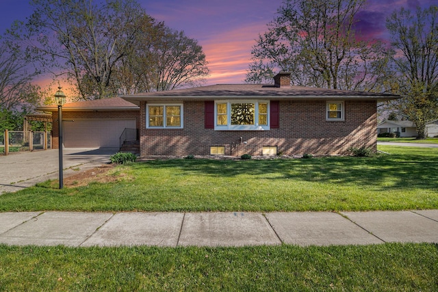 ranch-style home featuring a chimney, a lawn, brick siding, concrete driveway, and an attached garage