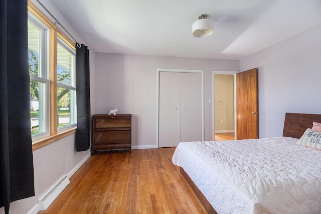 bedroom featuring a closet, baseboards, baseboard heating, and wood finished floors