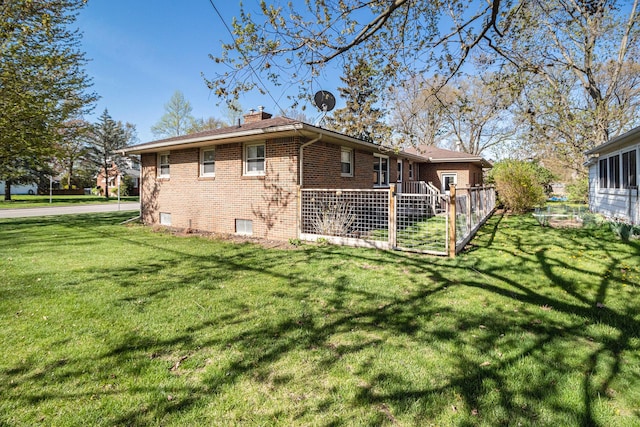 exterior space with a yard, brick siding, and a chimney