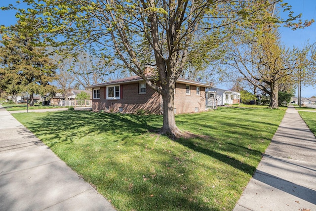 view of property exterior with a lawn, brick siding, and a residential view