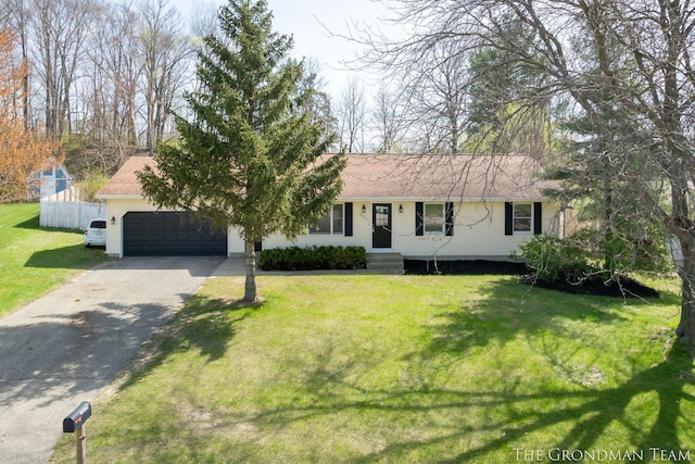 ranch-style home with fence, an attached garage, a front lawn, and aphalt driveway