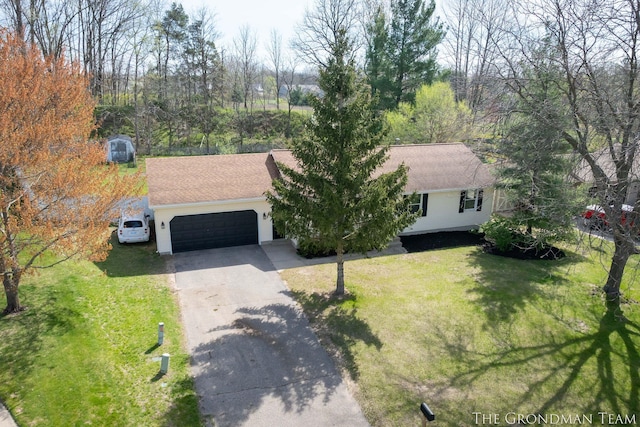 view of front of property featuring a garage, a shingled roof, a front yard, and concrete driveway