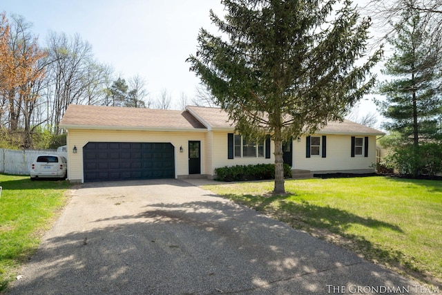 ranch-style home featuring a garage, fence, driveway, and a front yard