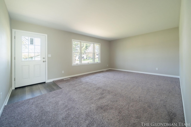 entrance foyer featuring baseboards, visible vents, and dark colored carpet