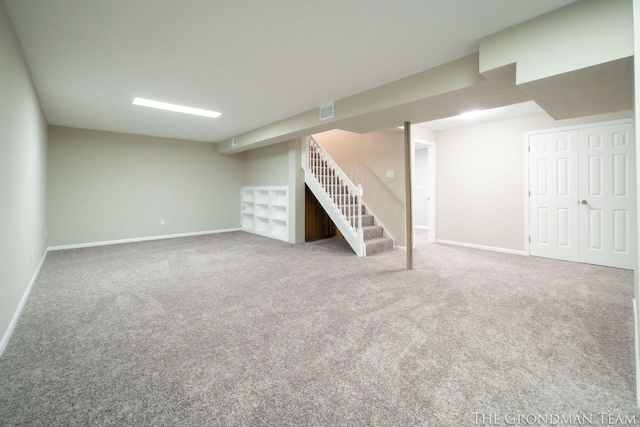 finished below grade area featuring stairs, baseboards, visible vents, and carpet floors
