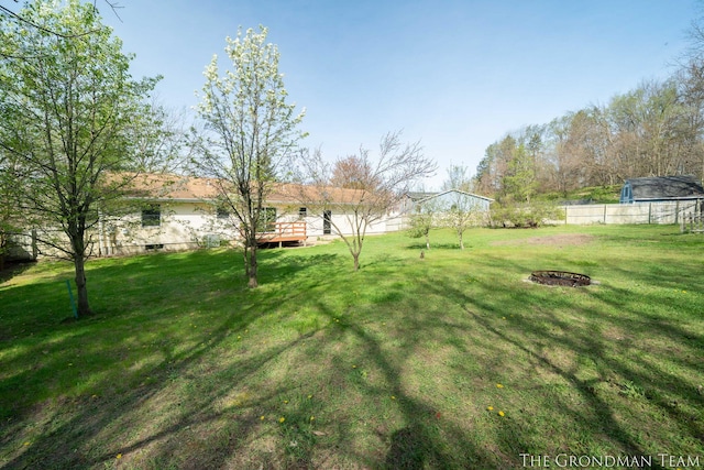view of yard with a fire pit, a wooden deck, and fence