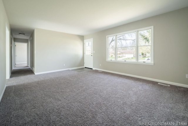 empty room with baseboards, visible vents, and dark carpet