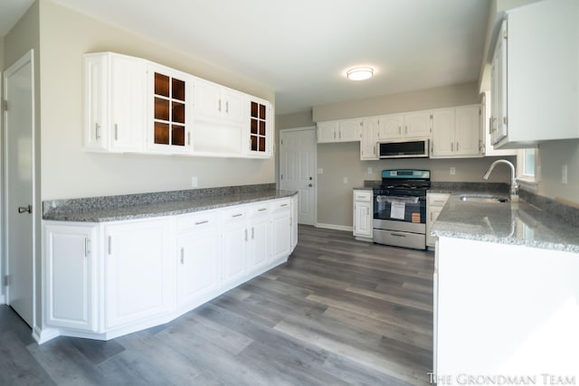kitchen featuring a sink, appliances with stainless steel finishes, wood finished floors, and white cabinets