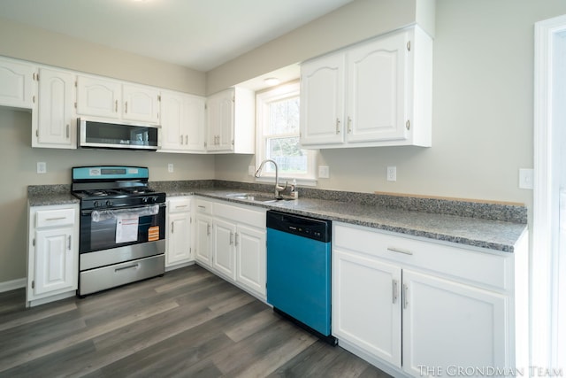 kitchen with dark countertops, dark wood-style floors, white cabinetry, a sink, and stainless steel appliances