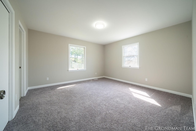 unfurnished bedroom with baseboards, multiple windows, and carpet