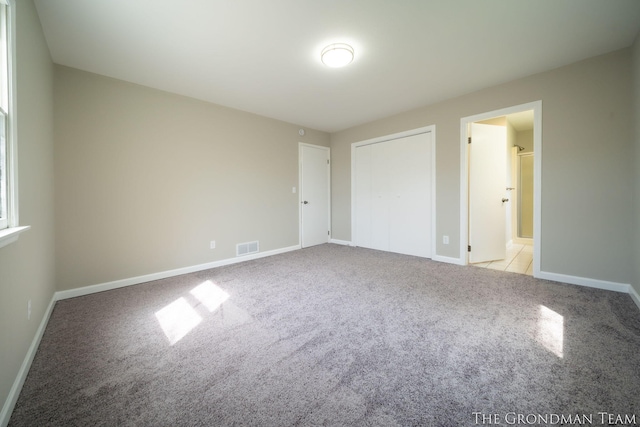 unfurnished bedroom with carpet floors, baseboards, and visible vents