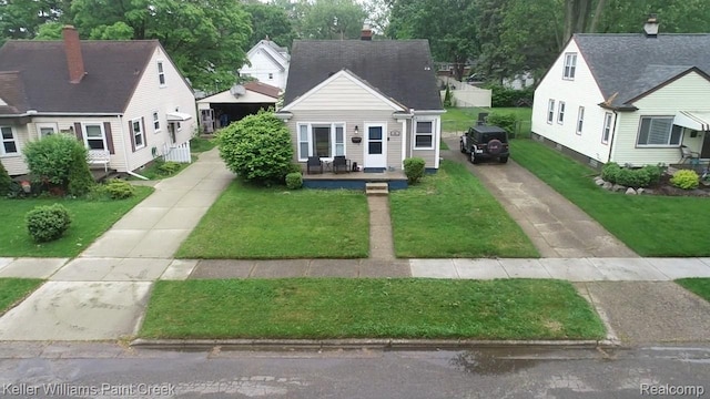43 Canfield Dr, Mount Clemens, MI 48043 - cape cod house featuring driveway, a front lawn, a chimney, and roof with shingles