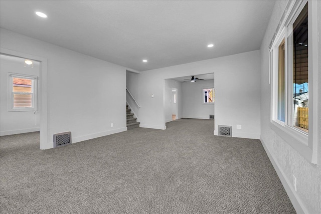 2061 E Whittemore Ave, Burton, MI 48529 - unfurnished living room with stairway, a wealth of natural light, carpet flooring, and visible vents