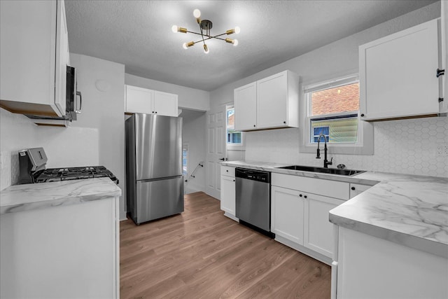 2061 E Whittemore Ave, Burton, MI 48529 - kitchen with an inviting chandelier, decorative backsplash, light wood-style floors, a sink, and stainless steel appliances