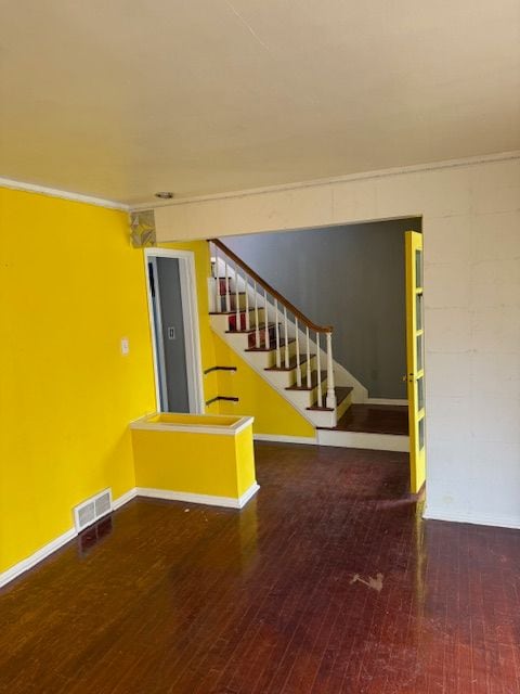 basement with crown molding, hardwood / wood-style floors, stairs, baseboards, and visible vents