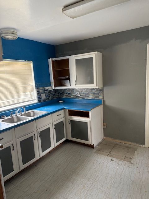 kitchen with a sink, tasteful backsplash, open shelves, and white cabinets