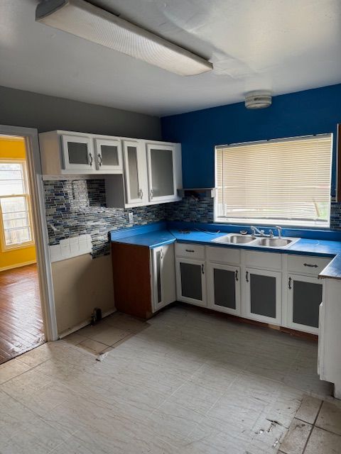 kitchen with a sink, white cabinetry, and tasteful backsplash