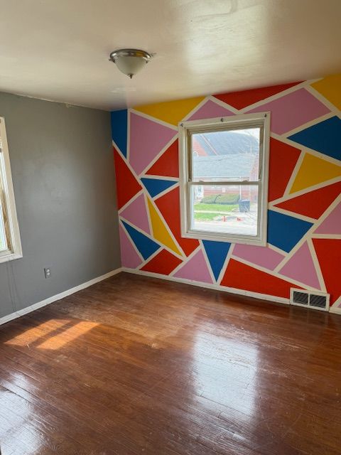 spare room with baseboards, visible vents, lofted ceiling, and hardwood / wood-style floors