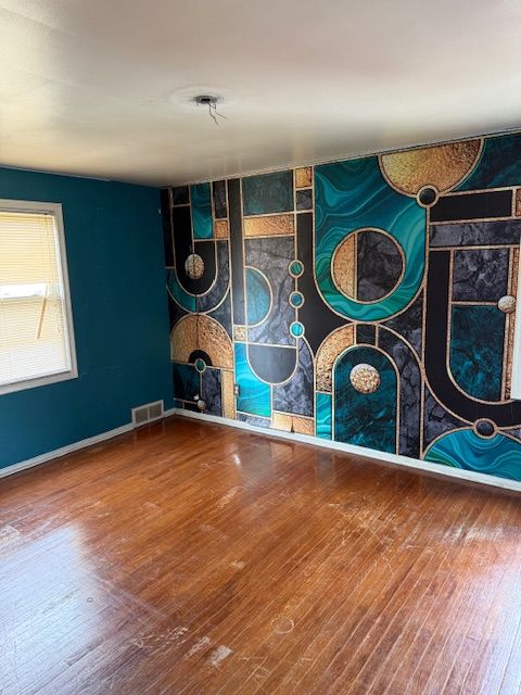 empty room with visible vents, baseboards, and hardwood / wood-style floors
