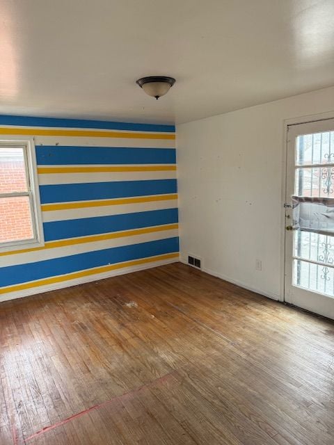 spare room with visible vents, a wealth of natural light, and wood finished floors