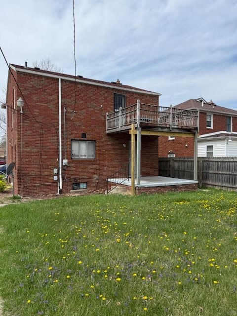 rear view of house with fence, a yard, a patio area, and brick siding