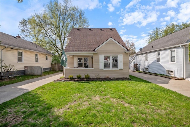 view of front of property with roof with shingles, fence, and a front yard