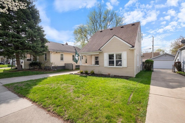 bungalow-style home with a front yard, roof with shingles, an outbuilding, central air condition unit, and a detached garage