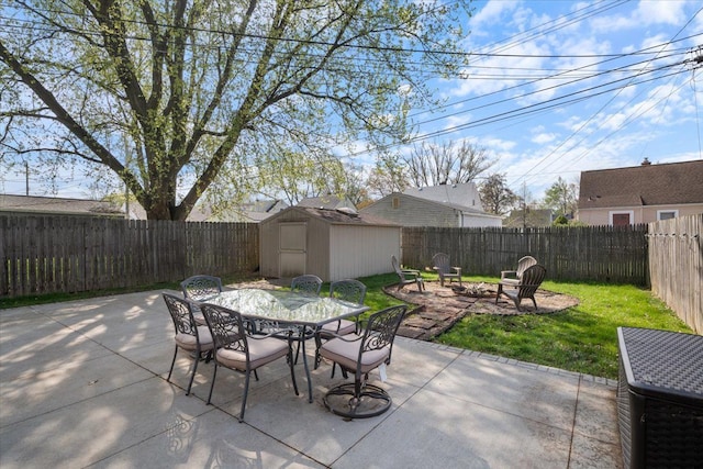 view of patio / terrace with a fenced backyard, a storage unit, an outbuilding, and outdoor dining area