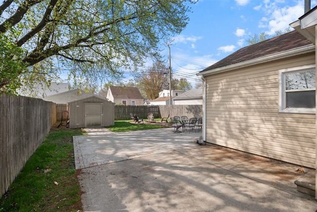 view of patio featuring a storage unit, a fenced backyard, and an outdoor structure