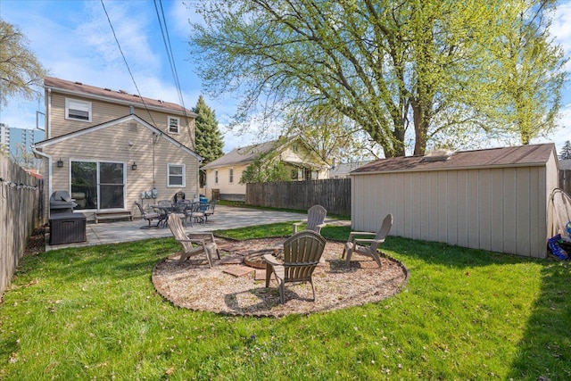 view of yard with a storage shed, an outbuilding, a fenced backyard, a patio, and a fire pit