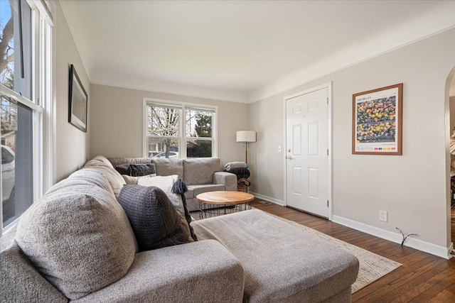 living area featuring arched walkways, baseboards, and hardwood / wood-style floors