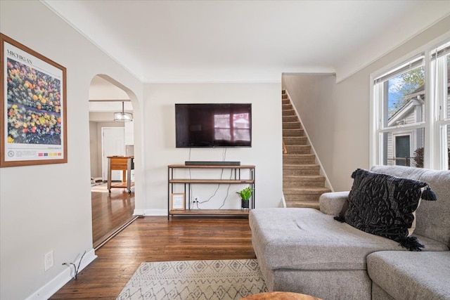living room with arched walkways, baseboards, stairway, and dark wood-type flooring