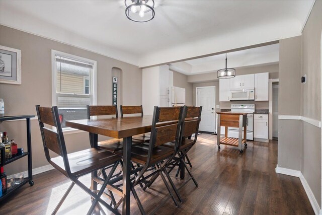 dining space with baseboards, arched walkways, and dark wood-style floors