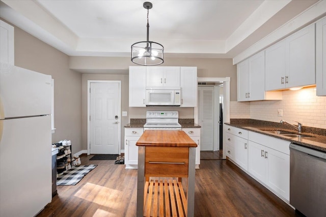 kitchen featuring dark wood-style flooring, white appliances, a raised ceiling, white cabinets, and a sink