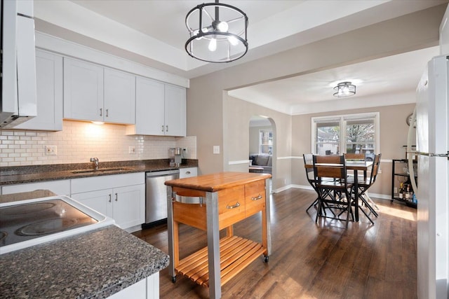 kitchen featuring backsplash, arched walkways, dishwasher, a sink, and dark wood-style floors