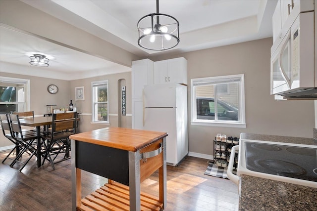 kitchen featuring wood finished floors, baseboards, white cabinets, a notable chandelier, and white appliances