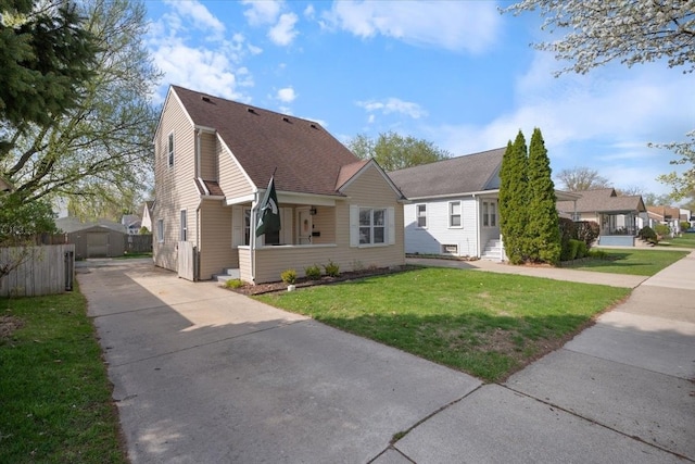 bungalow-style house with fence, roof with shingles, a front lawn, an outbuilding, and driveway